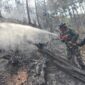 Personel Koramil 11 Kaliwiro bersama warga menyemprot sisa bara api saat proses pendinginan lahan bekas kebakaran di Bukit Bluwuk, Desa Kaliguwo, Kaliwiro, Wonosobo